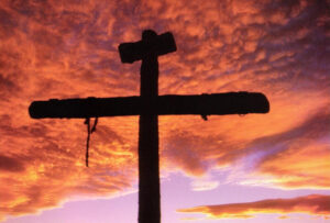 This is a picture of a cross that depicts the cross that Jesus was crucified on with red clouds in the background